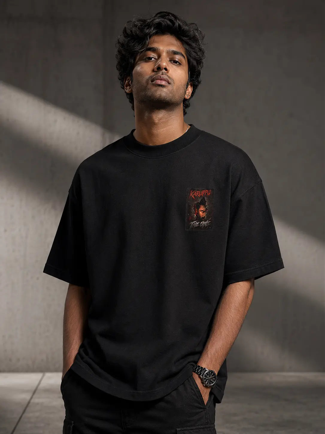 Man wearing a Suriya Karuppu black t-shirt with a graphic design against a gray background