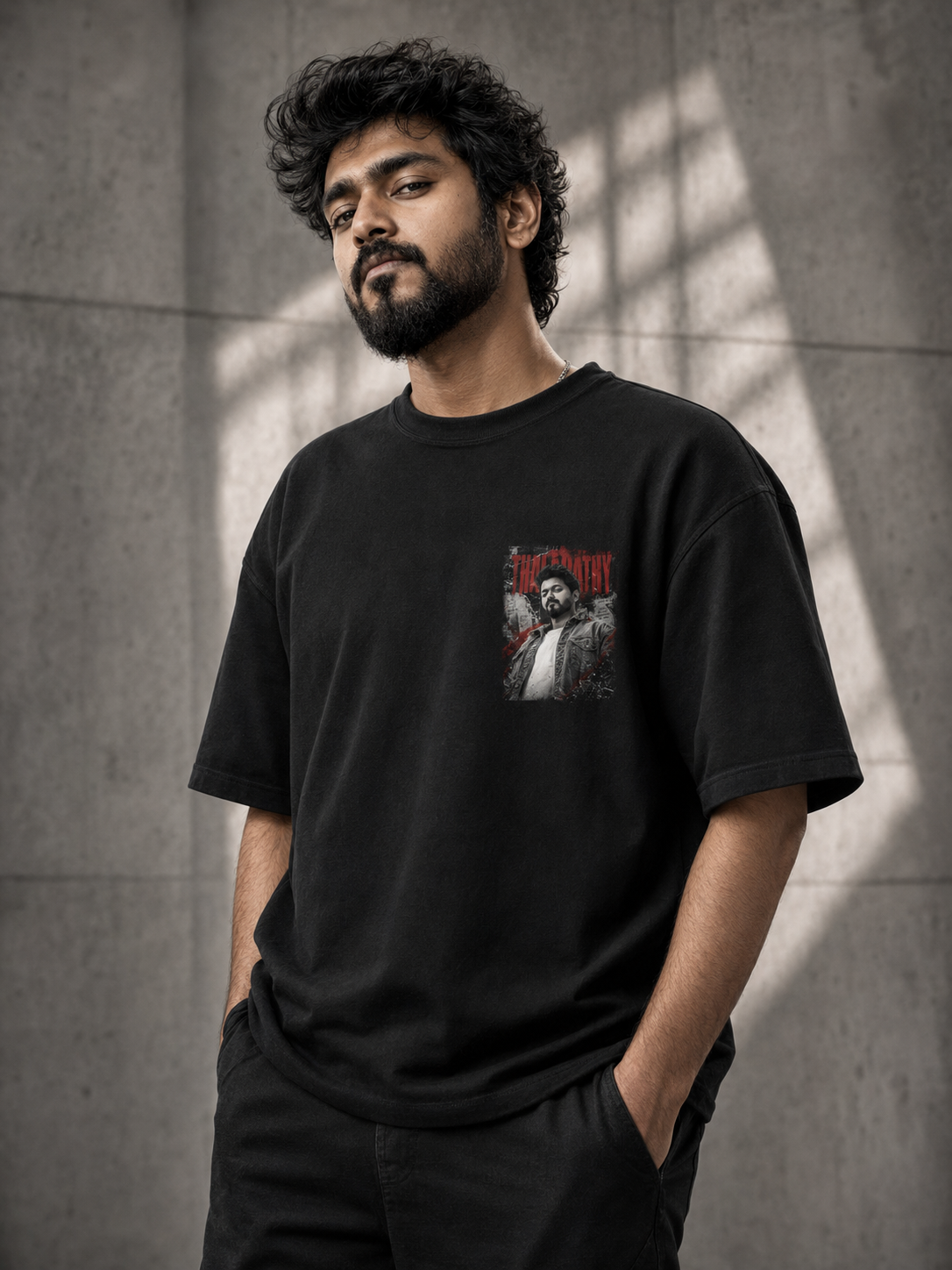 Person wearing a thalapathy vijay black t-shirt with a graphic design against a gray wall.