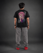 A person shown from the back wearing a black graphic T-shirt with a large anime-style character print in pink, purple, and white, paired with gray jeans and red shoes, against a dark gray studio background.